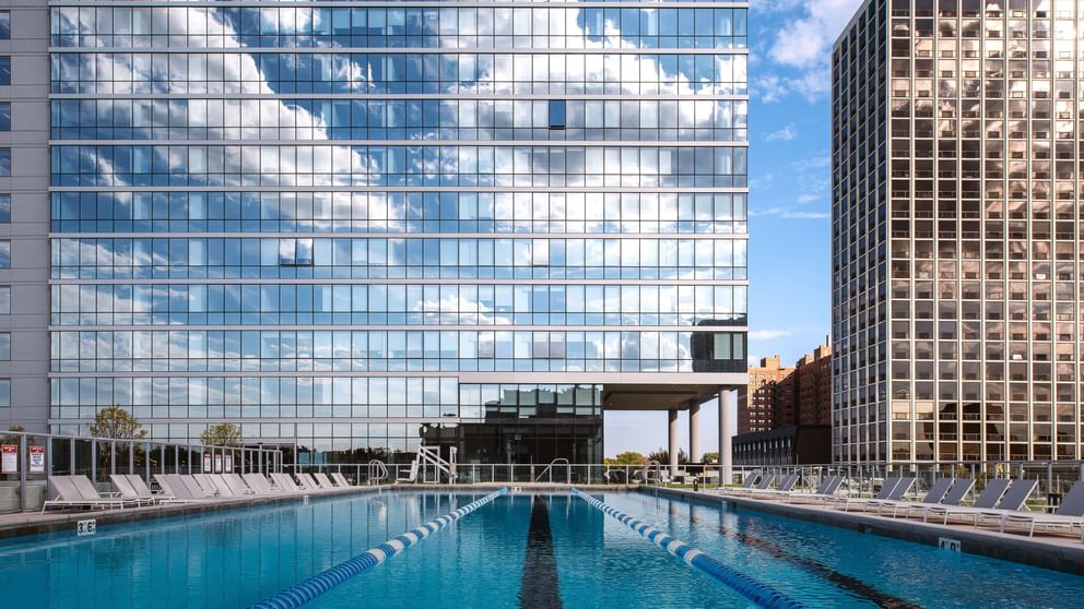 One-Bedroom Apartments in Uptown Chicago, IL - Eight Eleven Uptown - Full-Size Pool with TanningLounge Chairs and a View of Large Buildings.