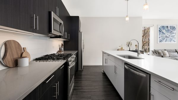 Uptown Chicago, IL, Apartments near Lake Michigan - Eight Eleven Uptown - Kitchen with QuartzCountertops, Stainless Steel Appliances, Two-Tone Cabinets, Tile Backsplash, and Wood-Plank Flooring.