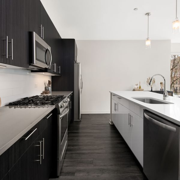 Uptown Chicago, IL, Apartments near Lake Michigan - Eight Eleven Uptown - Kitchen with QuartzCountertops, Stainless Steel Appliances, Two-Tone Cabinets, Tile Backsplash, and Wood-Plank Flooring.