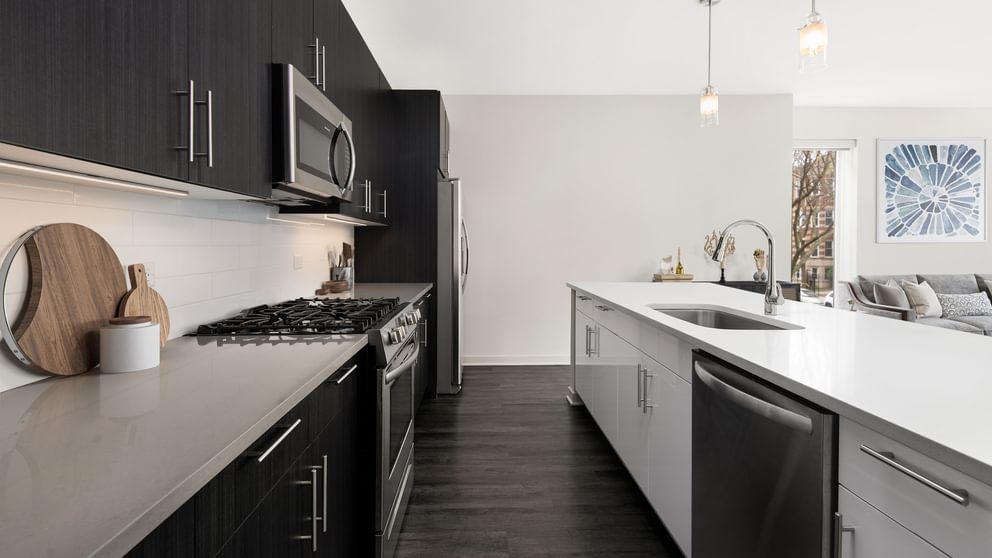 Uptown Chicago, IL, Apartments near Lake Michigan - Eight Eleven Uptown - Kitchen with QuartzCountertops, Stainless Steel Appliances, Two-Tone Cabinets, Tile Backsplash, and Wood-Plank Flooring.